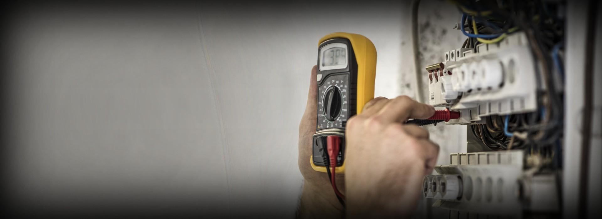 elektryk sprawdza miernikiem skrzynkę bezpieczników